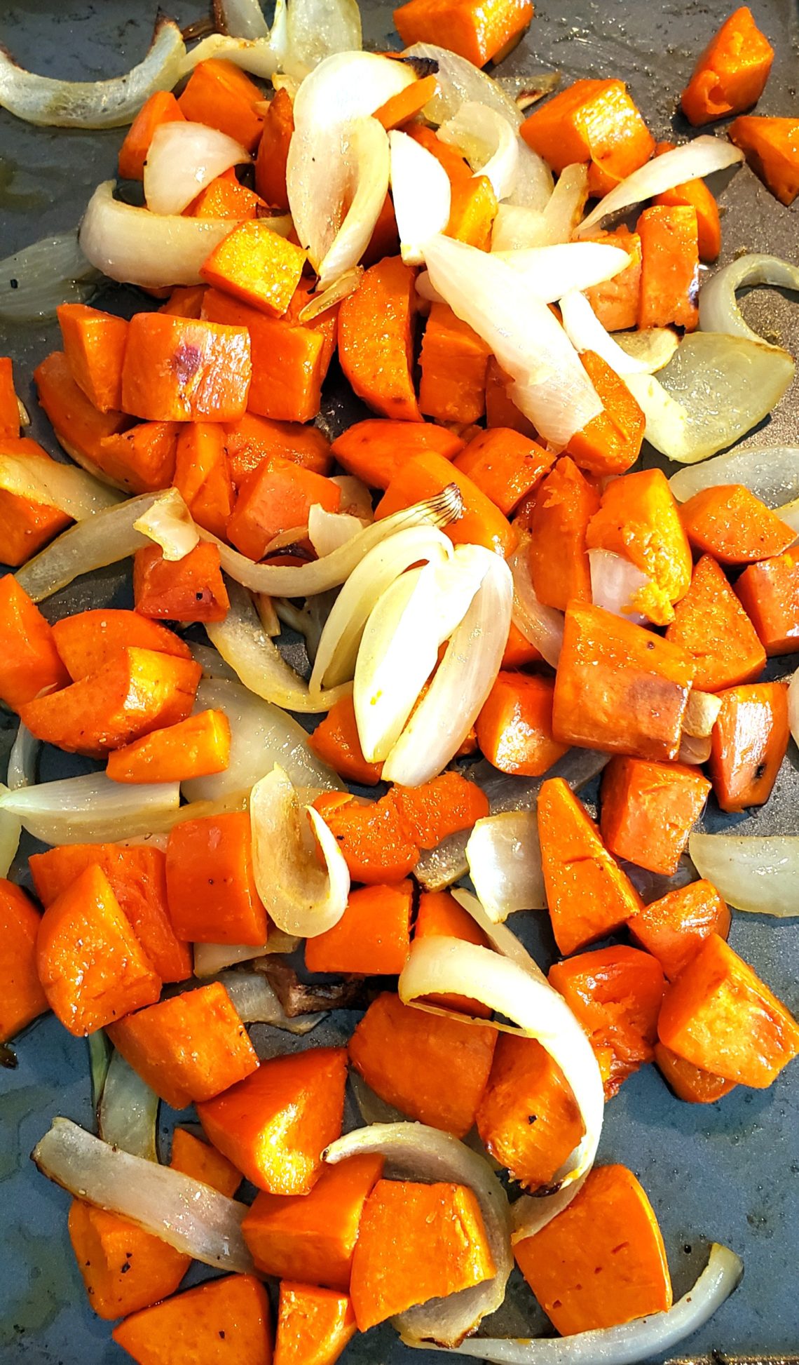 Cooked sweet potatoes, onion and garlic on a sheet pan.